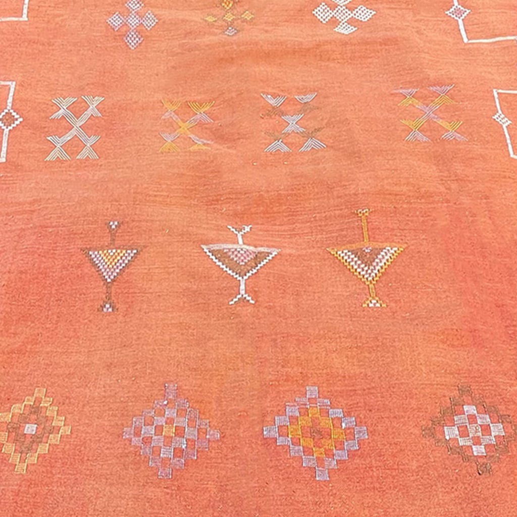 Close-up of a Moroccan sabra cactus silk rug in terracotta orange, featuring intricate handwoven geometric and tribal embroidery patterns