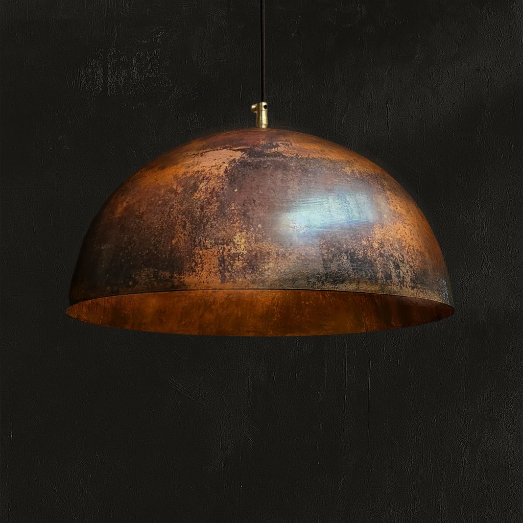 Handcrafted Moroccan pendant light with a wide dome silhouette, featuring a warm, weathered copper patina and a rich golden interior, set against a dark background