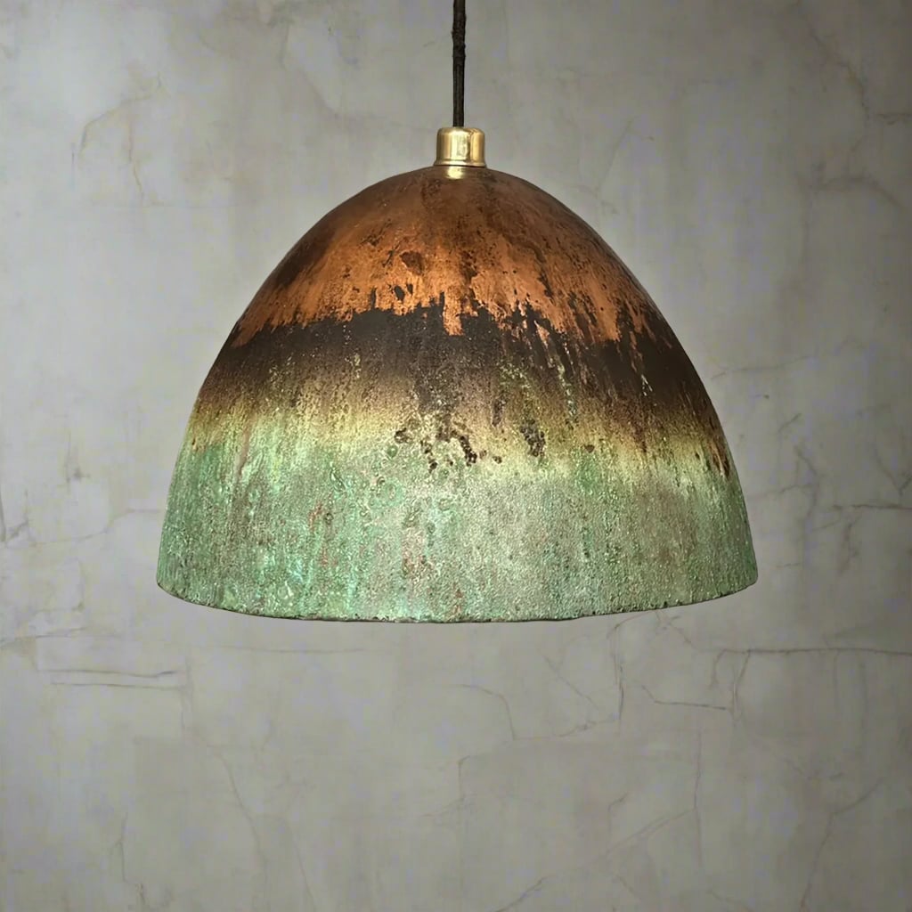 Oxidized green and copper hanging dome light with warm inner glow, set against a lightly textured plaster wall