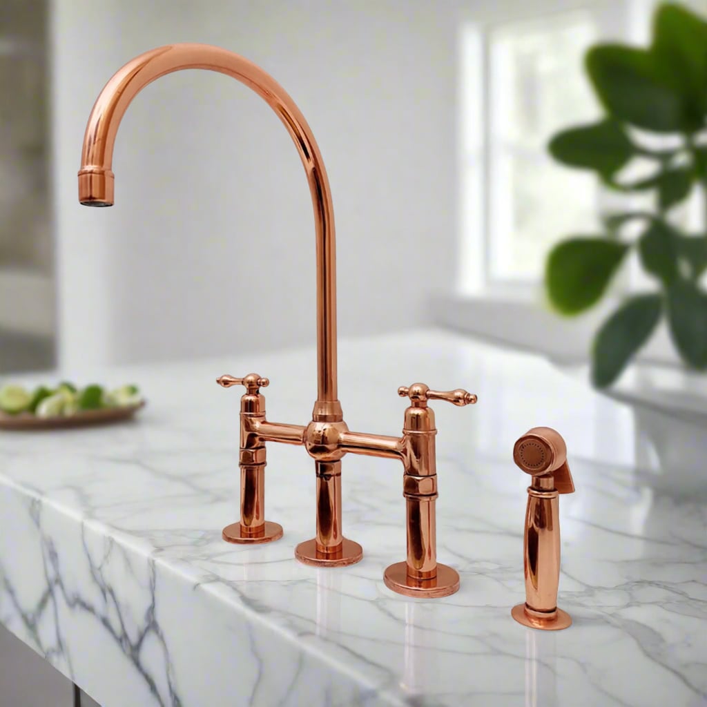 Polished copper bridge kitchen faucet with side sprayer installed on white marble countertop in a bright modern kitchen