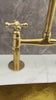 Video thmbnail of a close-up of a polished brass gooseneck kitchen faucet with cross handles, paired with a hammered brass sink set into a white marble countertop and gray stone backsplash