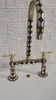 Thumbnail image of a video of a black and white inlay brass bridge faucet with lever handles, displayed against a black textured wall and white countertop.