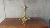 Video of a person wearing black gloves holding and showing the details of a polished brass dolphin-shaped faucet over a wooden surface
