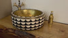 Video showing a decorative brass basin with black and white scalloped pattern on a wooden countertop, paired with a brass soap dispenser and vintage faucet