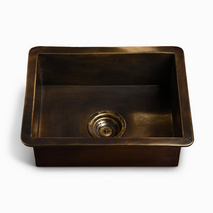 Rectangular brass kitchen sink with a centered drain and a smooth, dark antique finish