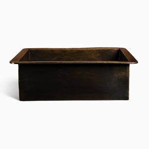 Front view of a rectangular brass sink with a dark antique finish and wide rim edges