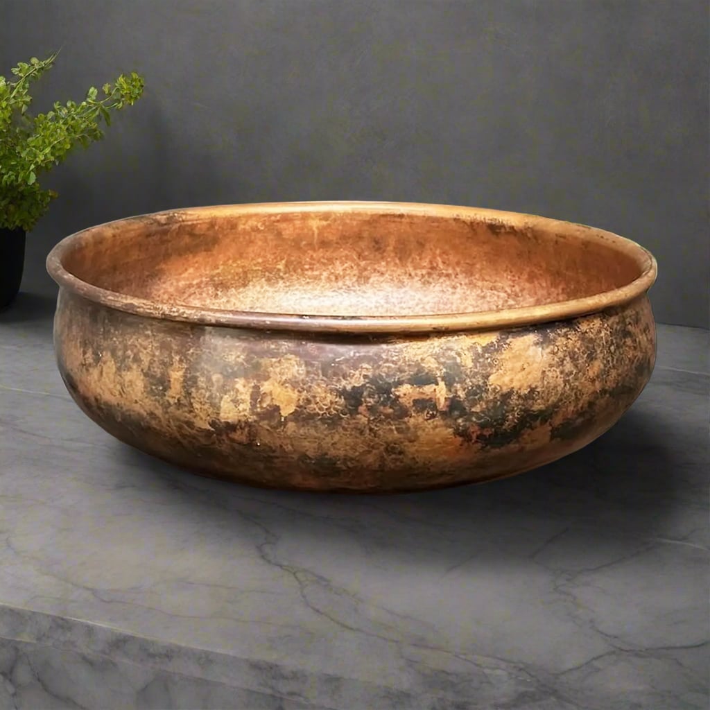 Handcrafted round antique patina copper sink with a wide rim and textured finish on a gray stone countertop