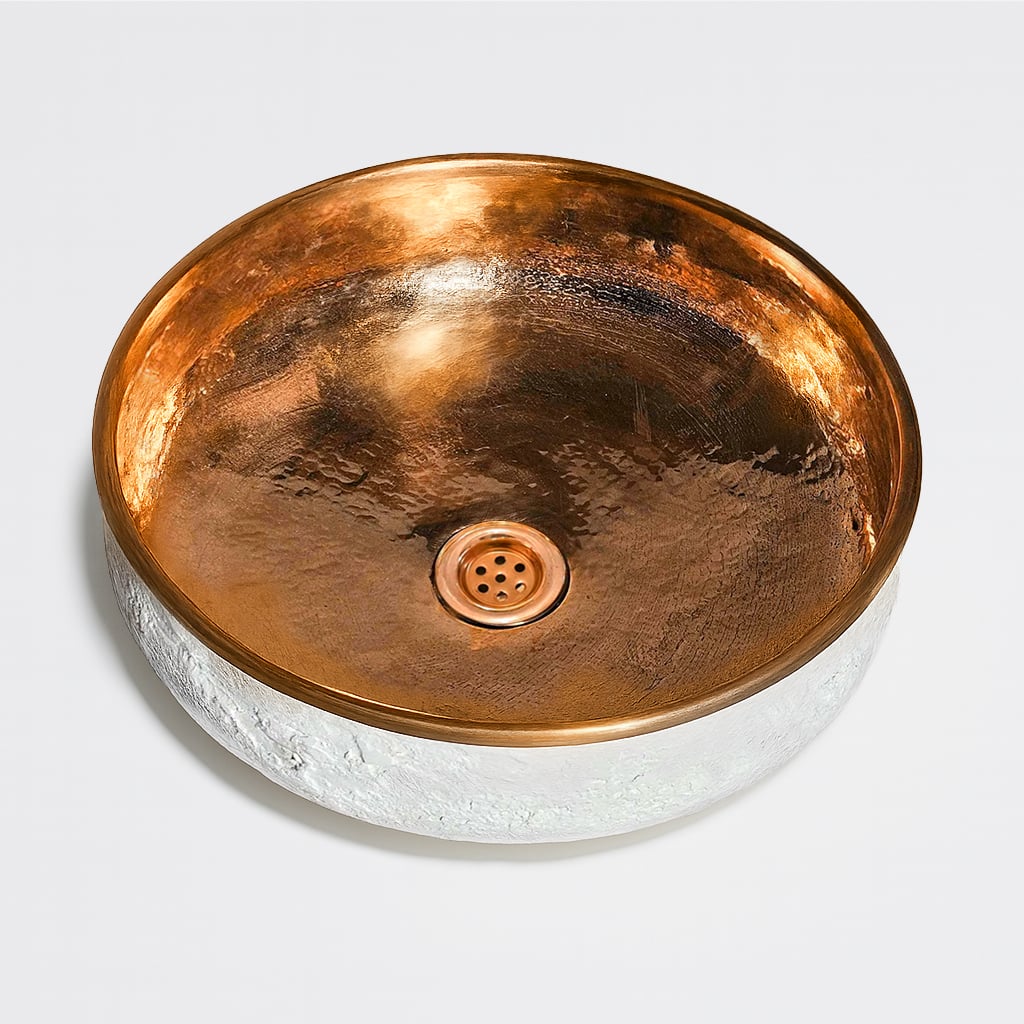 Top view of a round basin with a hammered copper interior and textured white exterior, featuring a central drain for a modern artisanal look