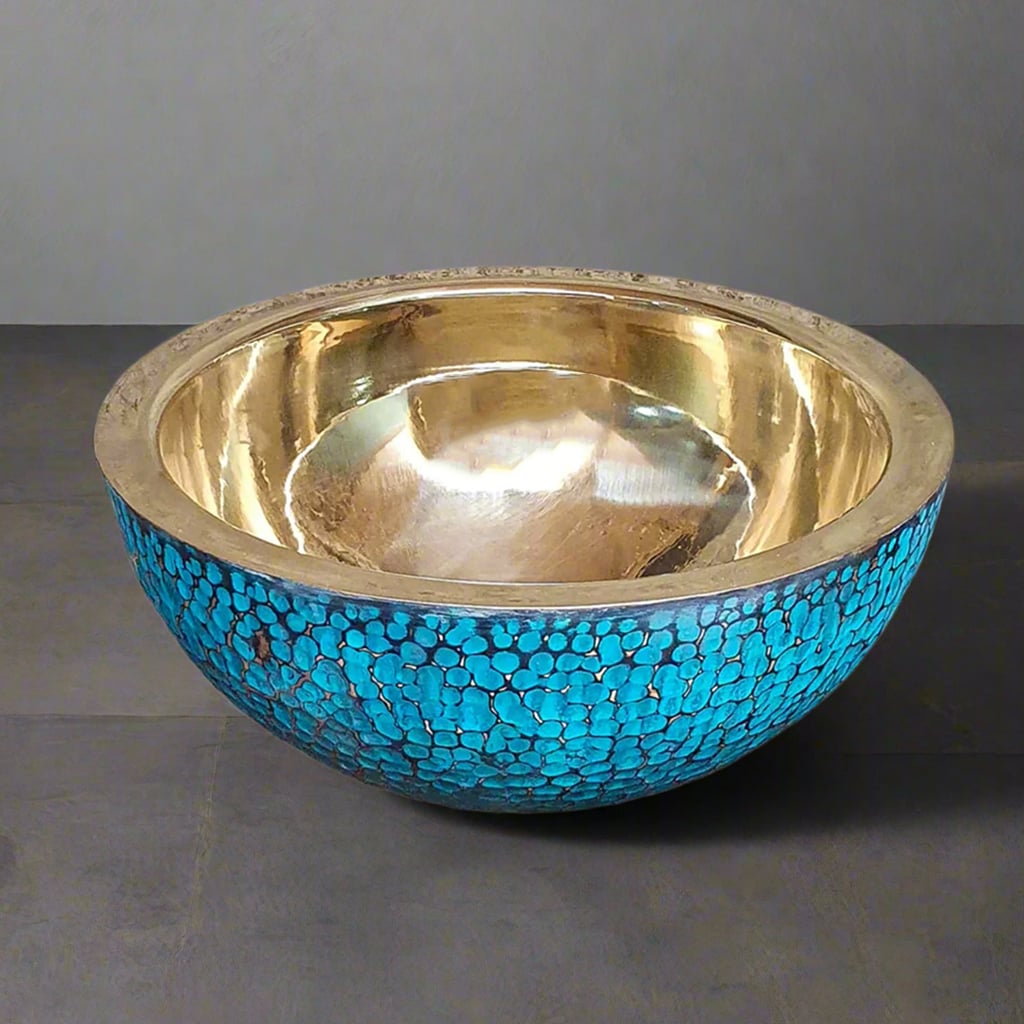 Top view of a round hammered brass basin with a shiny golden interior and turquoise patina exterior
