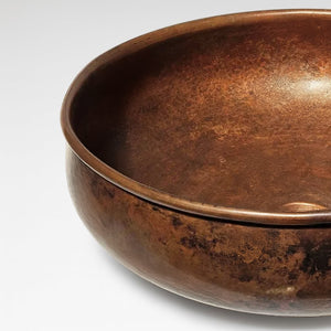 Handcrafted round copper basin with rich dark patina and smooth hammered texture, perfect for bathroom or kitchen sink design