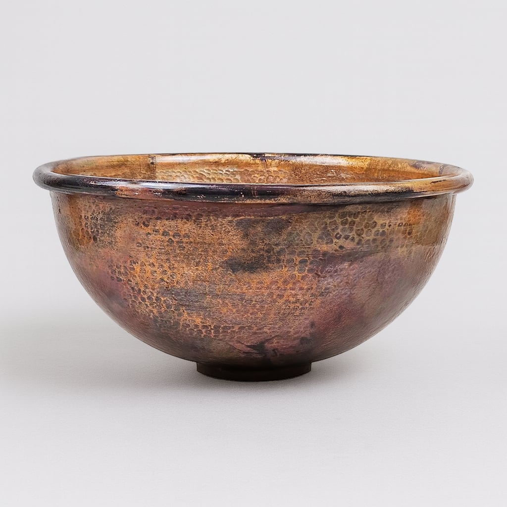 Hand-hammered round copper sink with a rich antique patina finish, showcasing artisanal texture and timeless rustic elegance