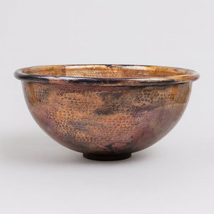 Hand-hammered round copper sink with a rich antique patina finish, showcasing artisanal texture and timeless rustic elegance