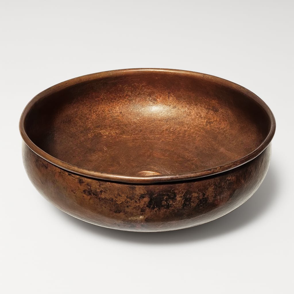 Round copper sink bowl with rich brown patina and smooth hammered finish, designed for timeless bathroom or kitchen interiors