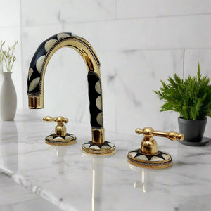 Luxurious three-hole bathroom faucet featuring mother of pearl inlay, gold finish, and classic lever handles, installed on a marble countertop