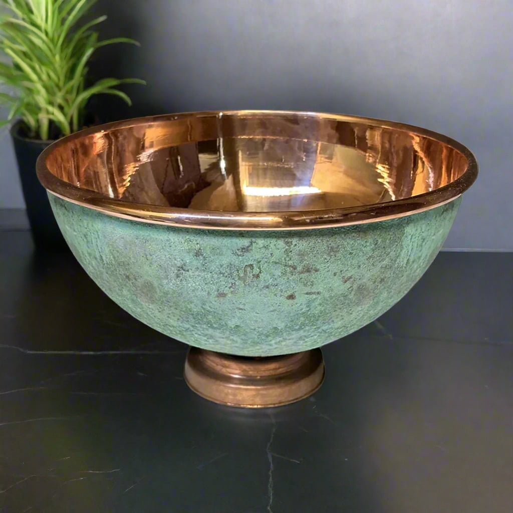 Round verdigris copper sink with glossy hammered interior displayed on a dark countertop