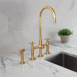 Elegant brass kitchen faucet set with side spray hose installed on white marble countertop with backsplash and potted plant