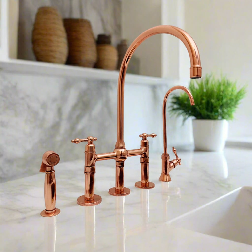 Traditional copper kitchen faucet with side sprayer and drinking spout, styled on a marble counter with a green plant in the background