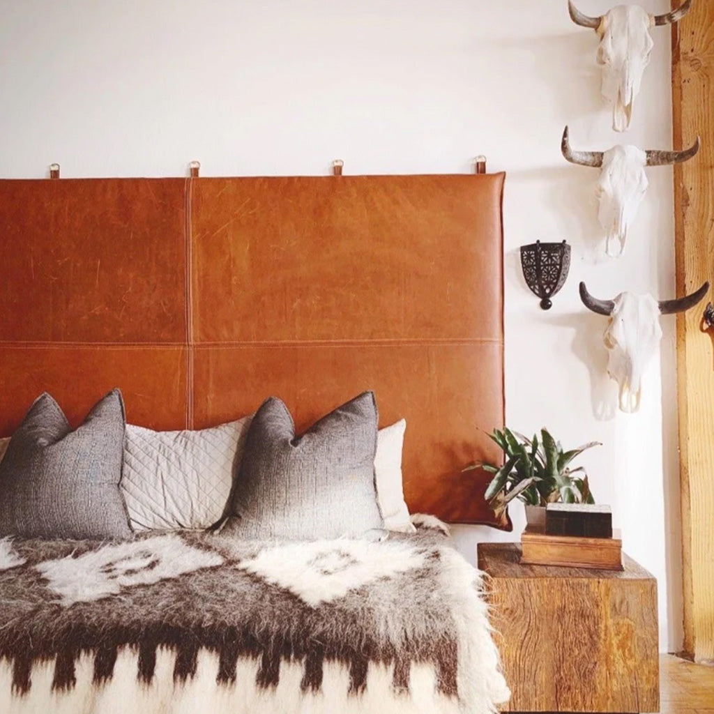 Cozy bedroom with soft plaid, warmth blanket, pillows on king-size bed with hanging leather headboard - Moroccan Interior.