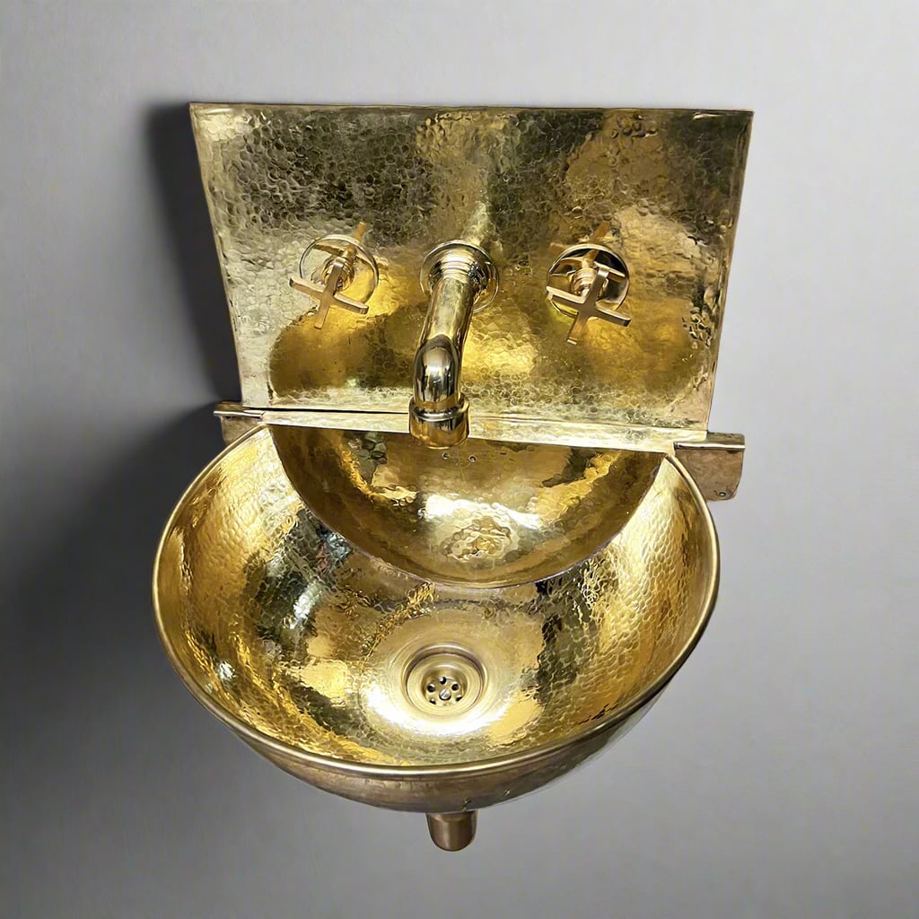 A commercial packshot of a wall-hung hammered brass sink with polished golden finish, brass faucet, and cross handles