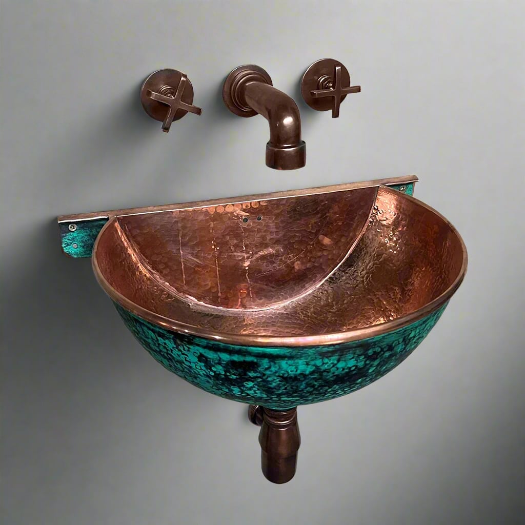 Wall-mounted hammered copper sink with green patina exterior and polished copper interior, featuring copper faucet and cross handles