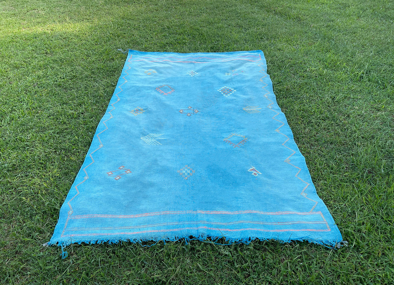 Sky blue Moroccan sabra rug with Berber motif against grass background - Moroccan Interior