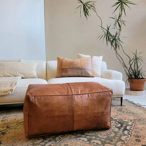 Moroccan Leather Bench in apartment living room with white sofas, colorful pillows, plaid, vase with plant - Moroccan Interior