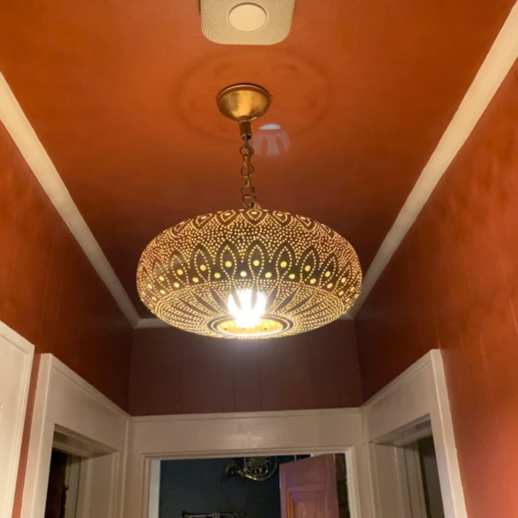 Moroccan brass pendant light hanging from the living room ceiling - Moroccan interior.