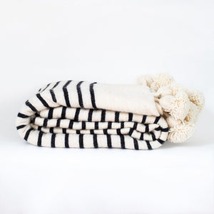 White and black Moroccan Pom pom blanket against a white background - Moroccan Interior