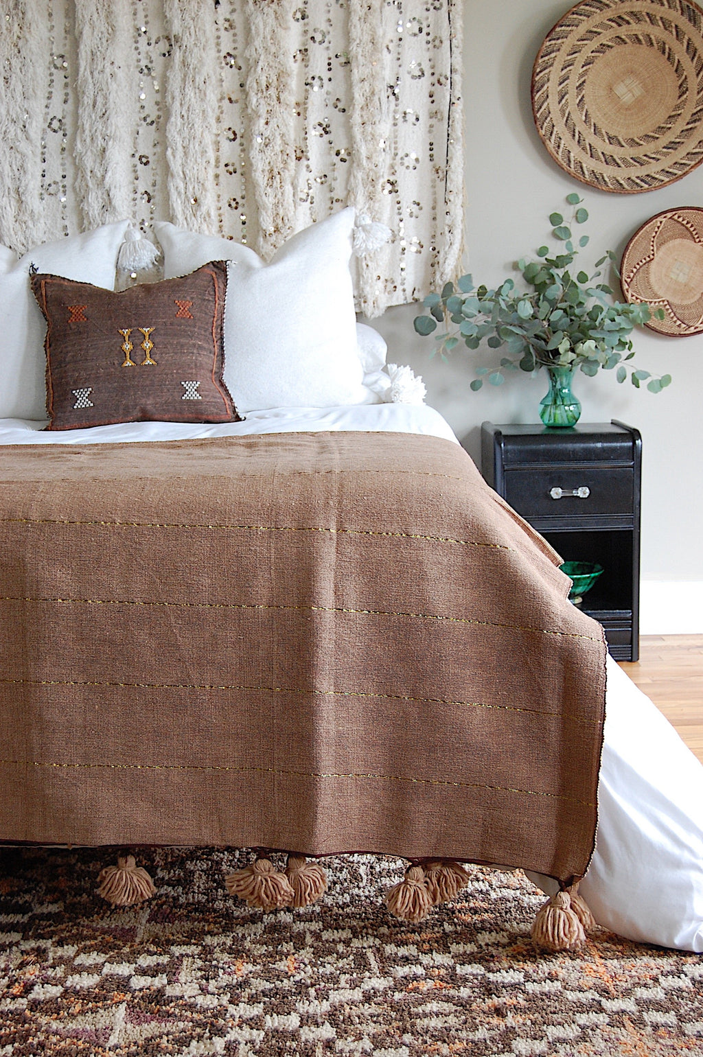 Beige Moroccan Pom pom blanket on top of a bed with pillows in a bedroom with berber furniture - Moroccan Interior