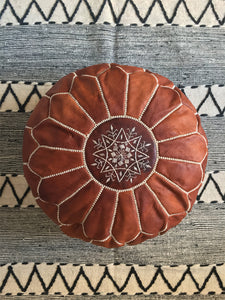 Dark tan round leather pouf on top of a berber wool rug - Moroccan Interior