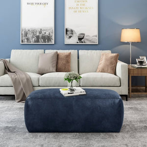 Contemporary living area: 3-seat sofas with pillows, large picture frames on blue wall, central dark blue leather pouf - Moroccan Interior