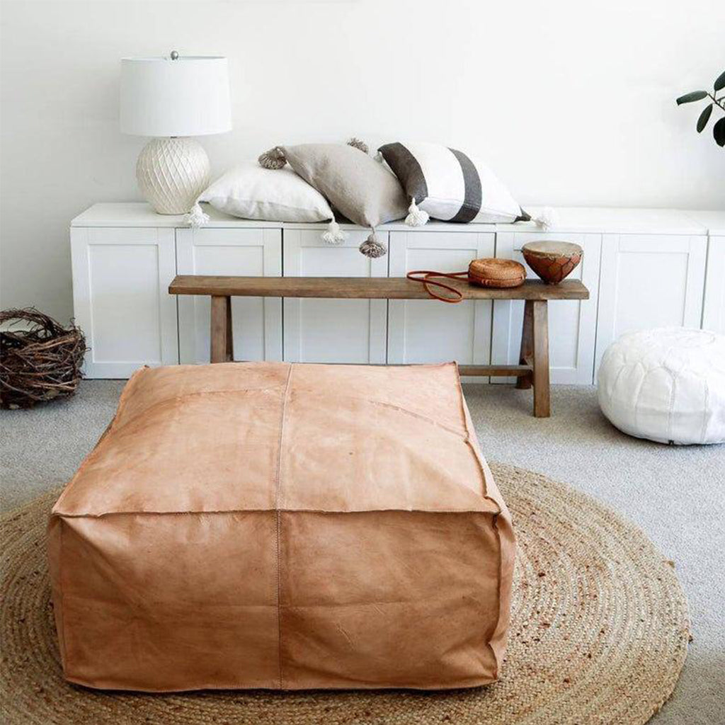 Square Leather Pouf on top of a round jute rug in a living space of an apartment with furniture  - Moroccan Interior