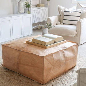 Square Leather Pouf on top of a round jute rug in a living space of an apartment with furniture - Moroccan Interior