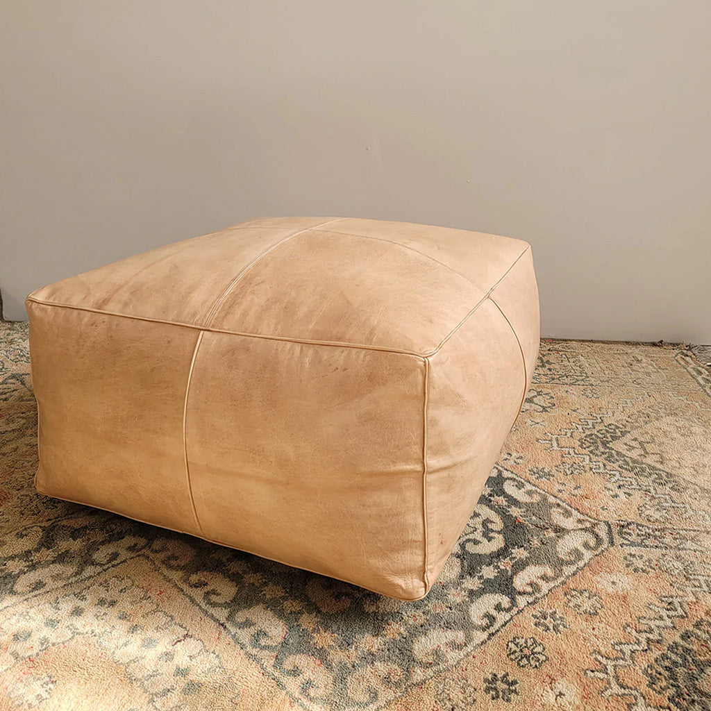 Square leather ottoman on wool rug in apartment room - Moroccan Interior