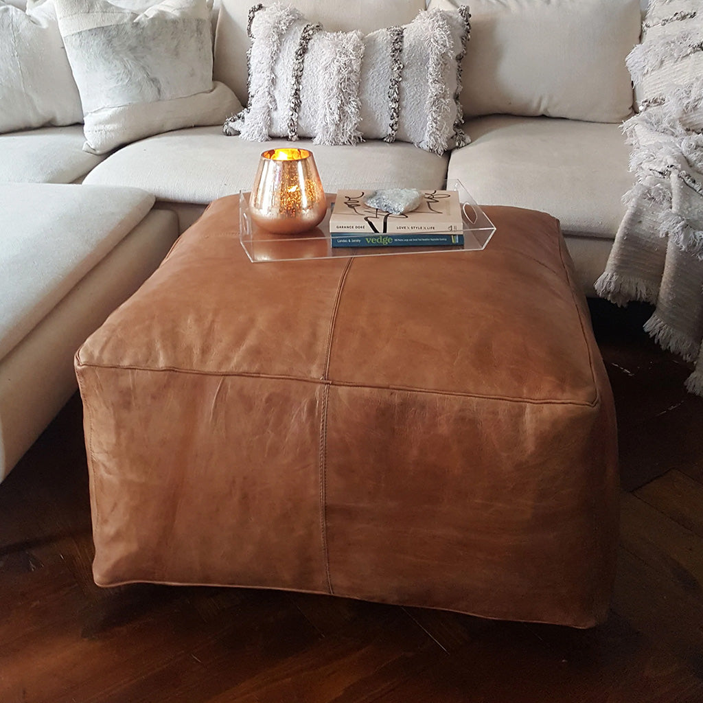 Square Leather Ottoman with a tray on top in a living space beside a white sofas with pillow - Moroccan Interior