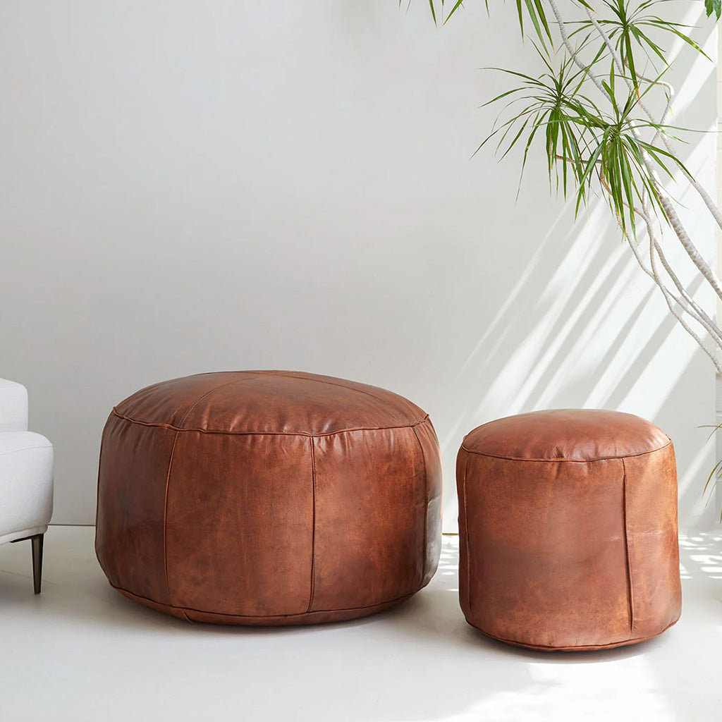 Set of two round leather poufs (medium and small) near a tree plant in living space - Moroccan Interior
